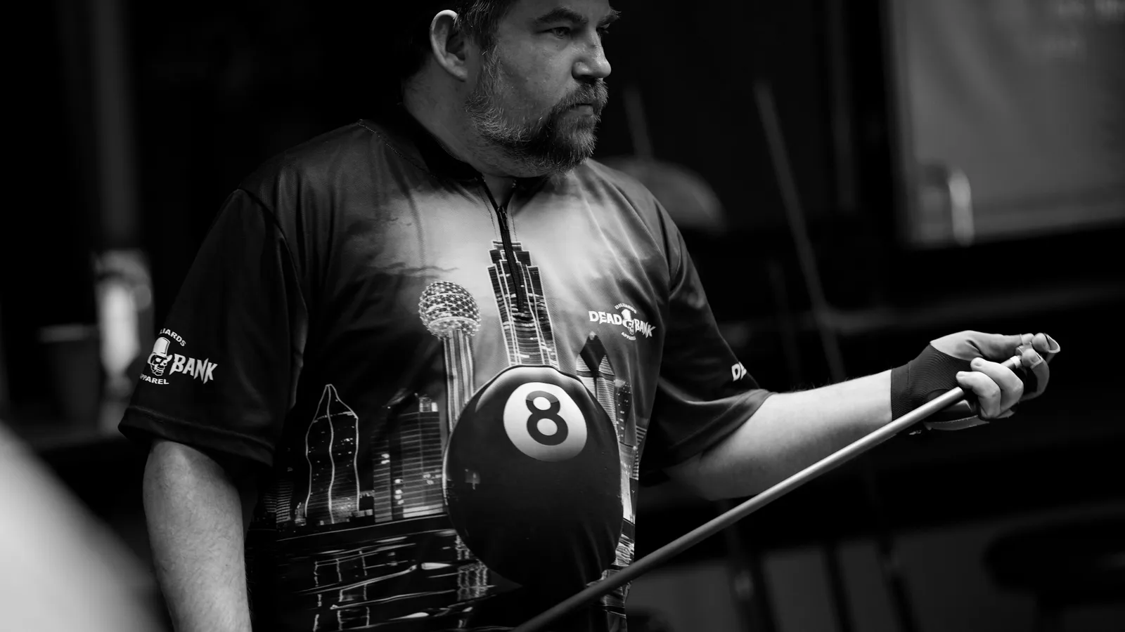 Player in the Dead Bank Dallas Skyline pool jersey holding a cue and 8-ball